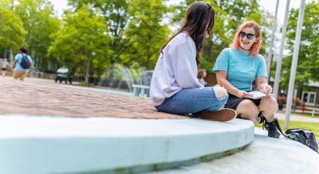 两名女学生正坐在韦伯中心前的台阶上聊天